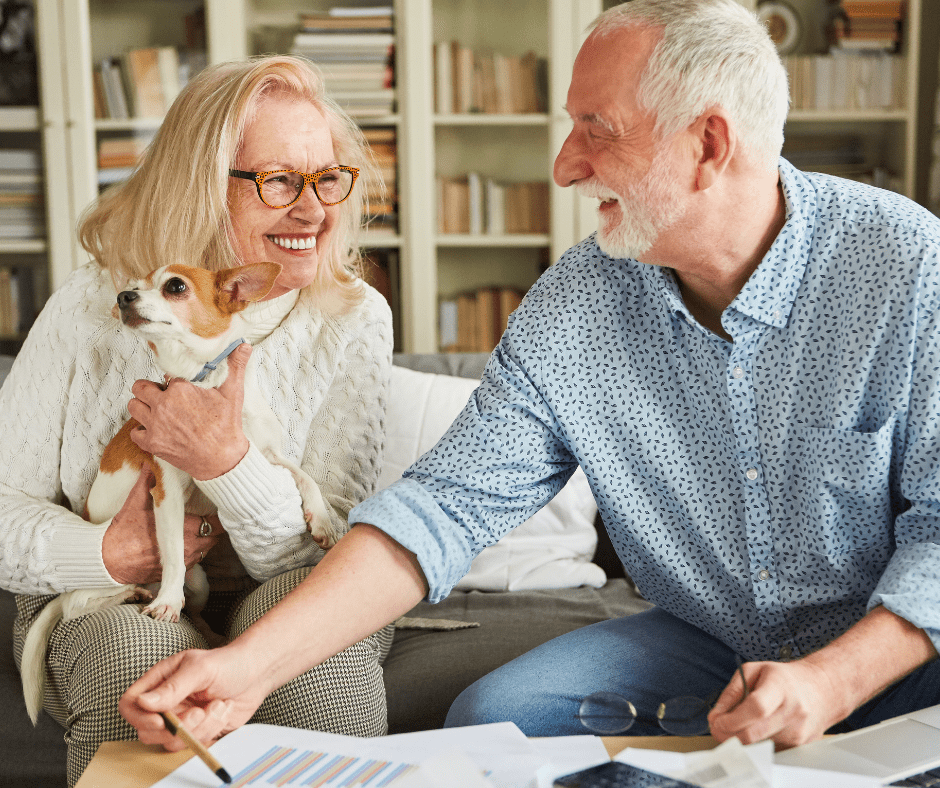 Elderly man and woman smiling and holding small dog